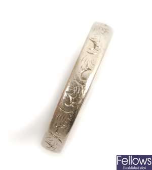 A band ring, with engraved scroll design detail