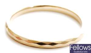 A 9ct gold slave bangle, with faceted detail.