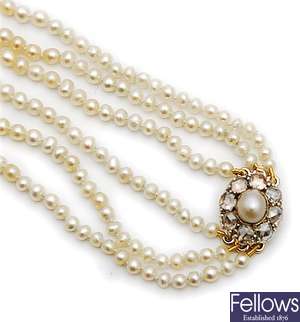 A three row graduated natural pearl necklet on an
