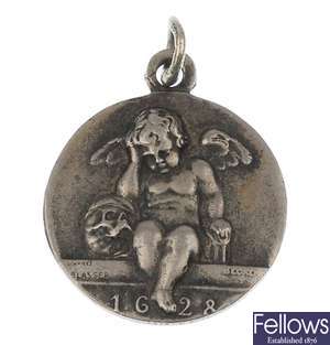 A token style pendant, depicting a cherub sat on