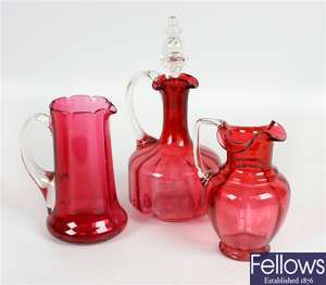 A 19th century cranberry glass jug and two other cranberry glass jugs