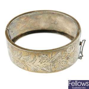 A late Victorian silver wide hinged bangle, a further hinged bangle and a longurad chain.