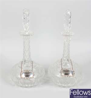 A pair of cut glass decanters with silver labels