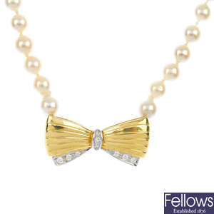 A cultured pearl single-strand necklace with diamond bow clasp.