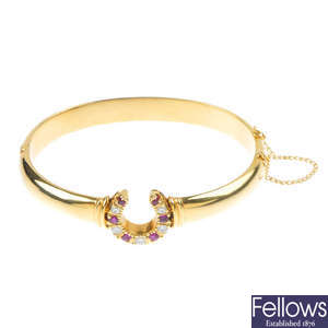 A 9ct gold ruby and diamond horseshoe bangle.