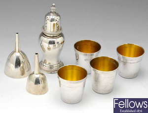 A modern silver caster, shot cups and two vanity funnels.