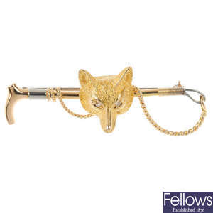 A diamond fox head and riding crop brooch.
