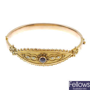 A late 19th century 9ct gold garnet and seed pearl hinged bangle.