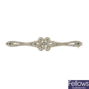 A diamond and emerald bar brooch.