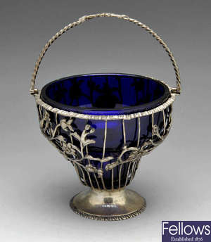 A George III silver swing handled sugar basket with blue glass liner.