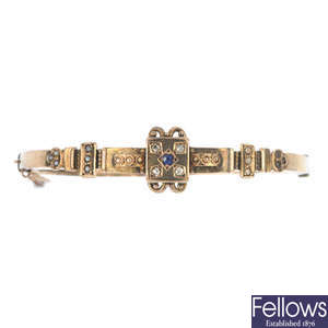 An early 20th century 9ct gold diamond, sapphire and split pearl hinged bangle.