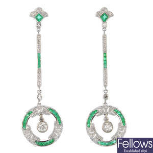 A pair of diamond and emerald ear pendants.