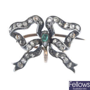 An early 20th century silver and 15ct gold, emerald and diamond bow brooch. 