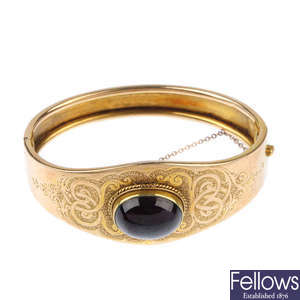 A late 19th century gold garnet hinged bangle.