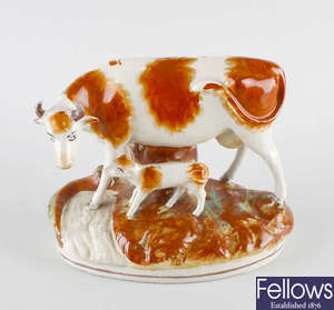 A Staffordshire figure group, modelled as a cow with calf. 