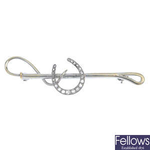 A diamond horseshoe and riding crop brooch.