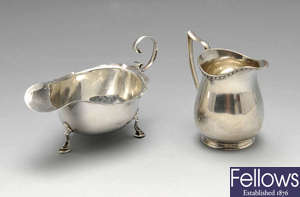 A 1920's silver cream jug and sauce boat, plus two silver peppers and a salt. 