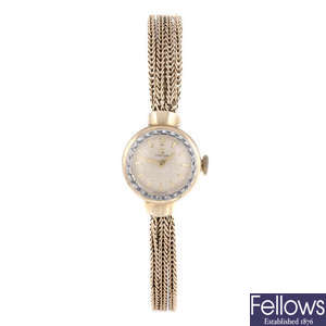 OMEGA - a lady's 9ct yellow gold bracelet watch with a pendent watch and brooch.