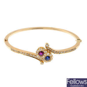 An early 20th century gold ruby, sapphire and diamond crossover bangle.