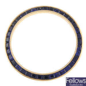 A yellow metal sapphire set bezel in the style of Rolex.