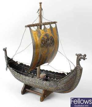 A box containing a brass counter, a model of a Viking longship or dragonship and assorted trophies.