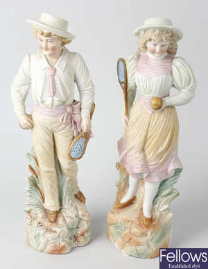 A pair of bisque figures, together with a pair of candlesticks.