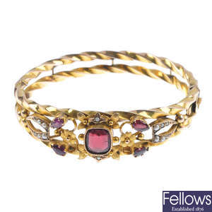 An Edwardian 9ct gold garnet and split pearl hinged bangle.