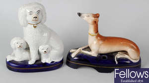 A 19th century Staffordshire pottery greyhound inkwell, together with a similar flatback group depicting a poodle with puppies. (2).