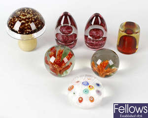 A group of seven glass paperweights.