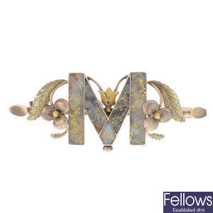 A late Victorian gold hardstone letter 'M' brooch, circa 1880.